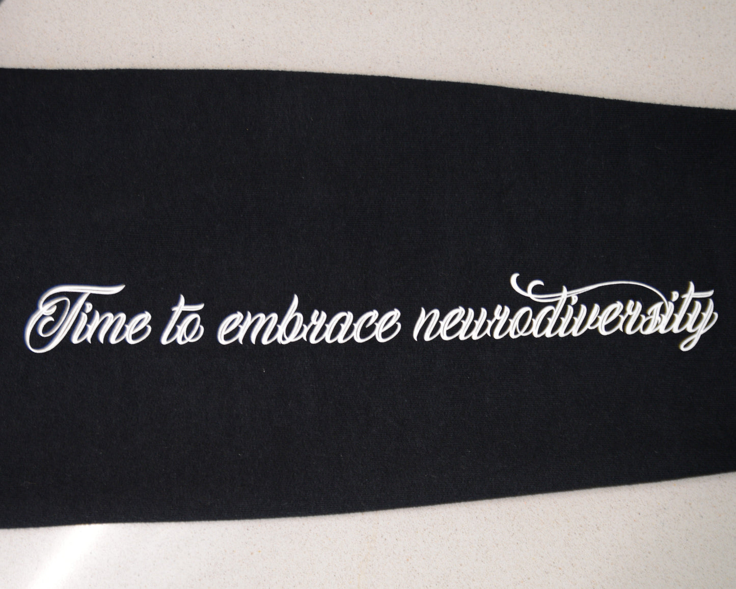Black ribbon with white text 'Time to embrace neurodiversity' on a white background